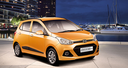 Side-front view of orange Grandi10 with lakeside view at night