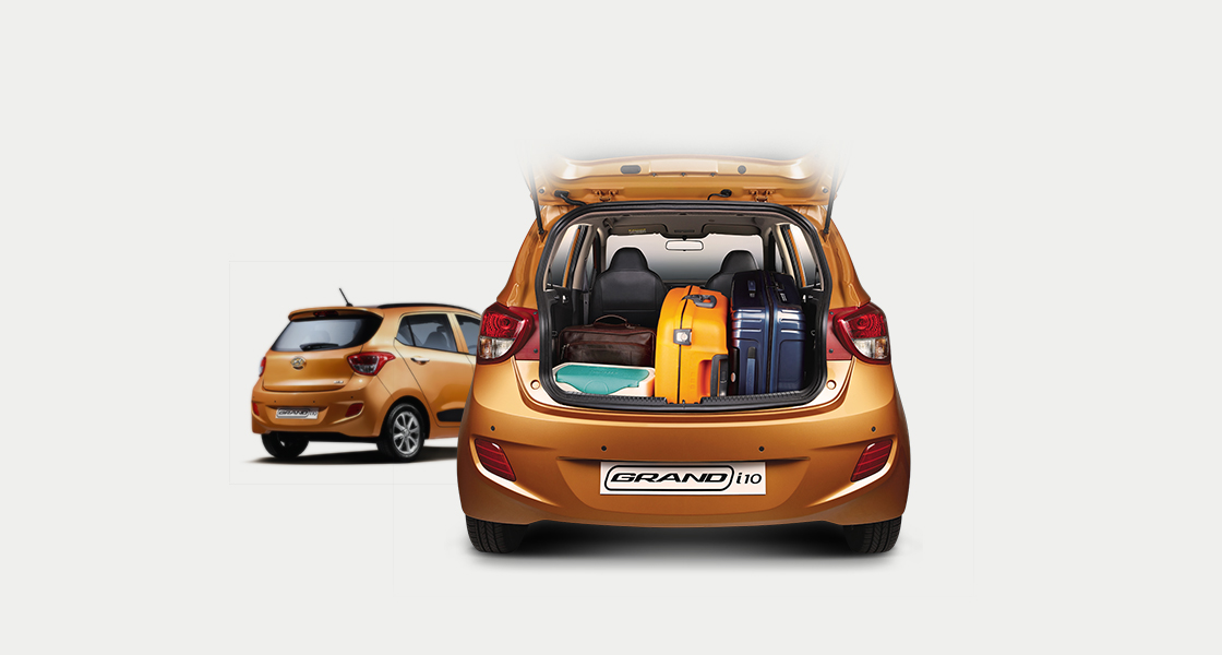 Two rear view of tangerine orange Grand i10 with many luggage loaded on the trunk